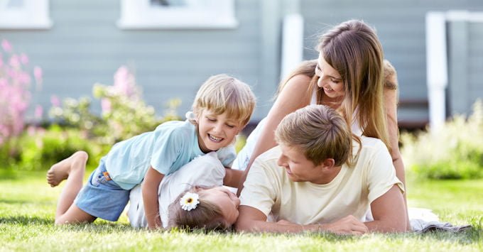 Family of mother, father, girl and boy lying in the grass and smiling at each other